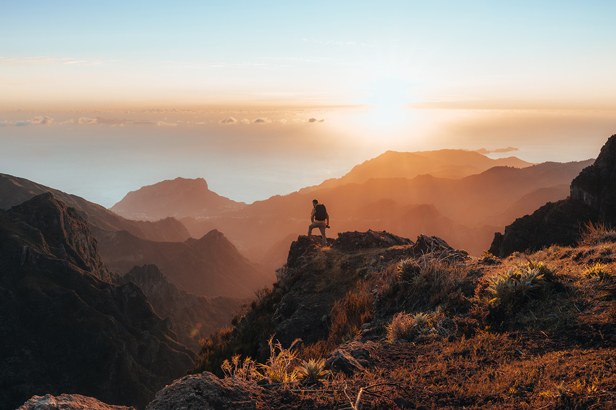 Sonnenaufgang auf Madeira – Wanderer auf dem Weg zum Pico Ruivo steht an einer spektakulären Klippe mit Blick in die Tiefe, beliebtes Ziel für Wanderreise und Aktivurlaub auf der Atlantikinsel